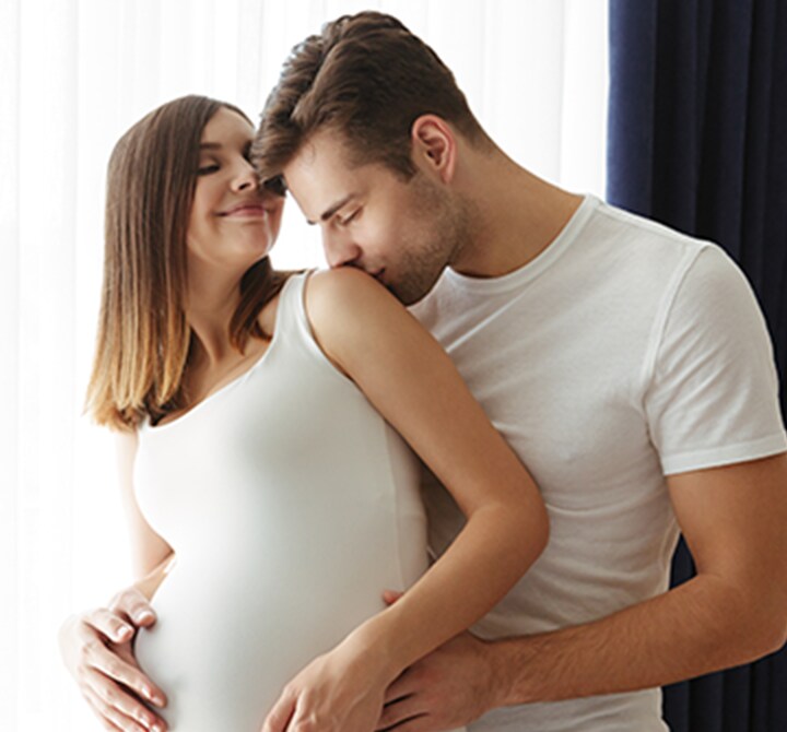 Ovem marido feliz beijando a esposa grávida 