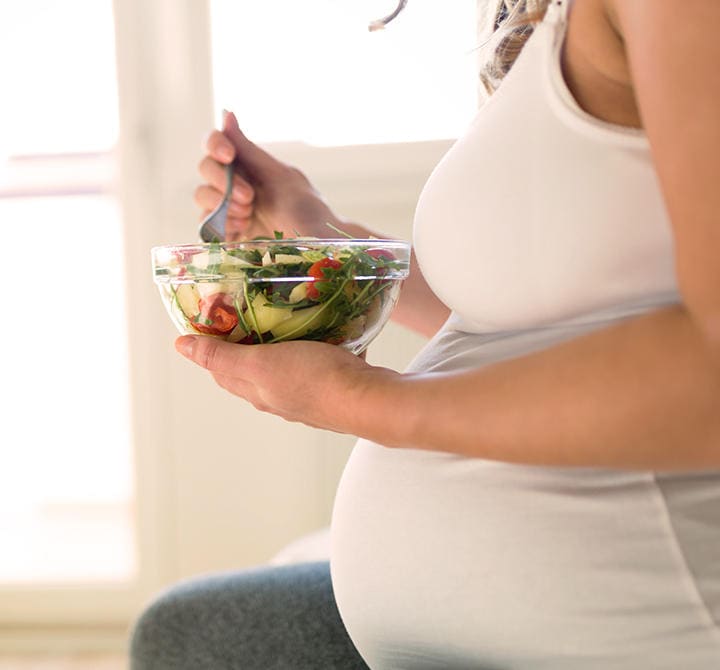 Mulher grávida em dieta saudável segurando salada